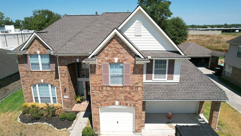 Two-story brick home in Spring, TX after a PL Roofing roof replacement