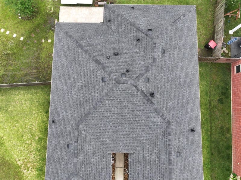 Drone photo of a finished hip roof with new gray architectural shingles, straight ridge lines and neatly flashed vents on Range Haven Ln in Porter, TX