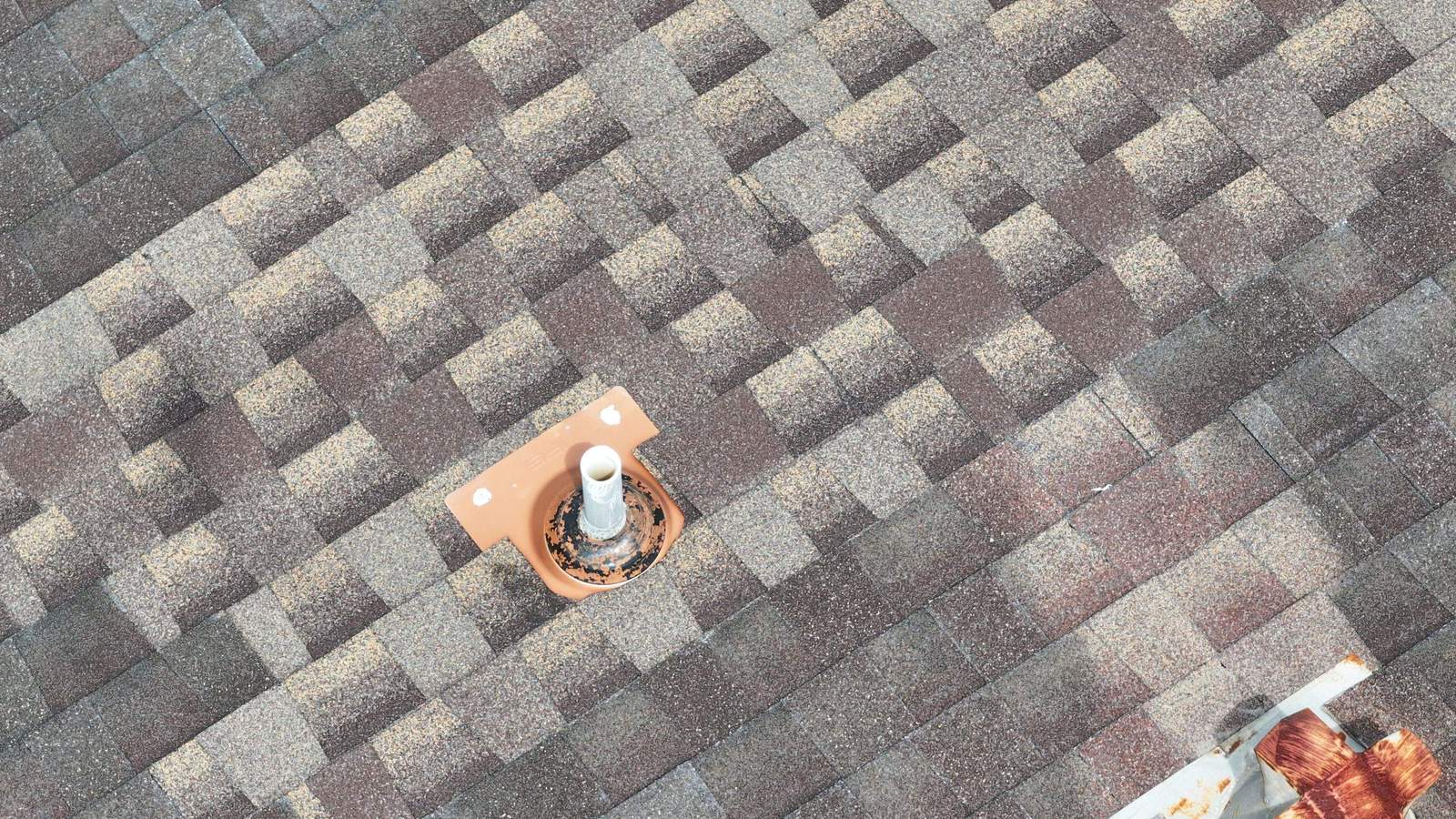 New pipe boot among patched, mismatched shingles on an older roof
