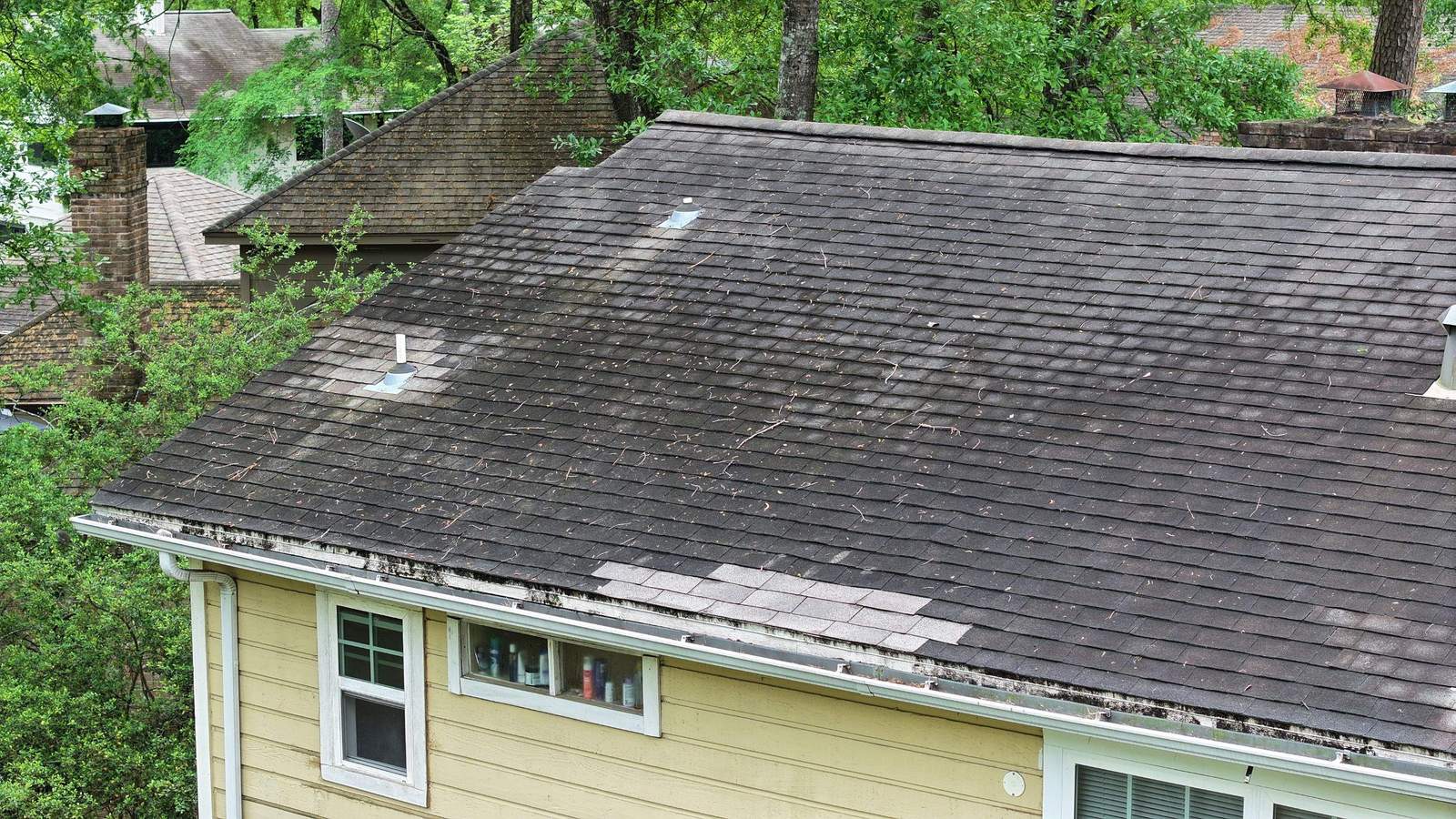 Stained, patched shingle roof with mismatched replacement shingles