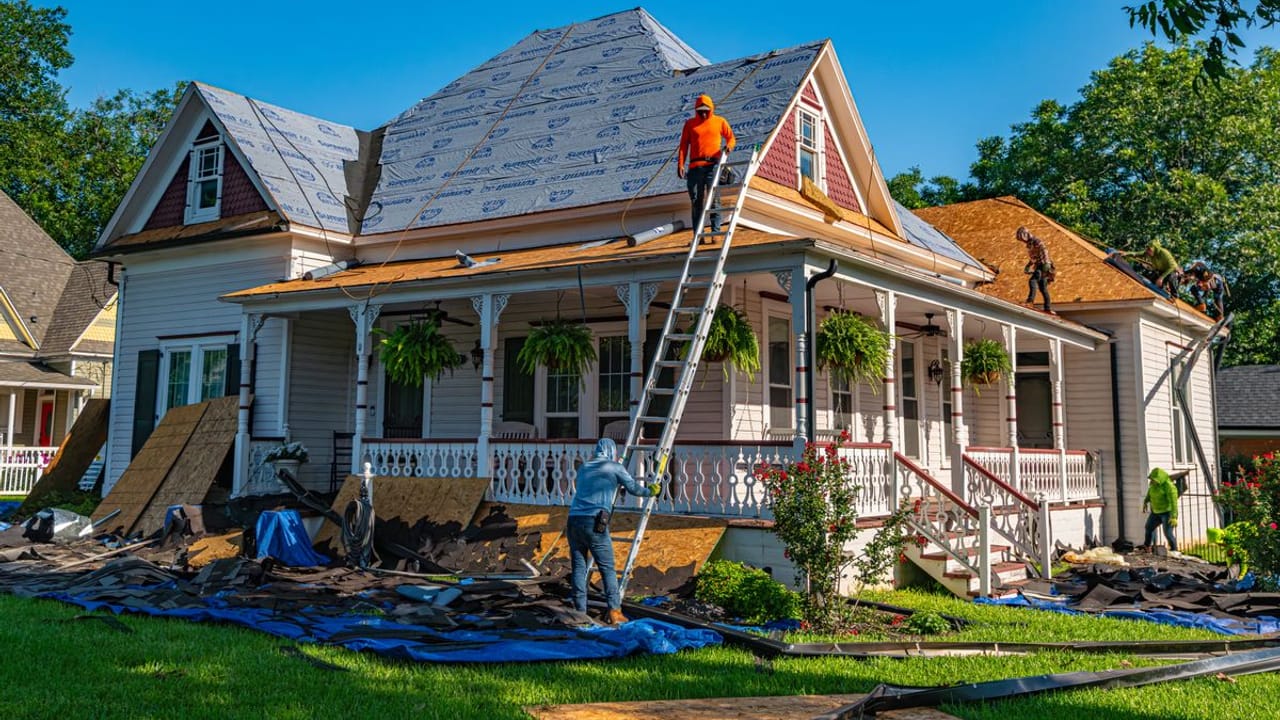 PL Roofing crew completing an asphalt shingle roof replacement on a Houston-area home, with synthetic underlayment installed and the yard protected by tarps