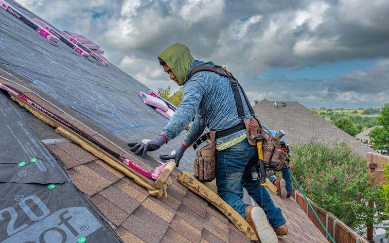 Bundles of asphalt shingles and roofing materials staged on a residential roof ready for installation